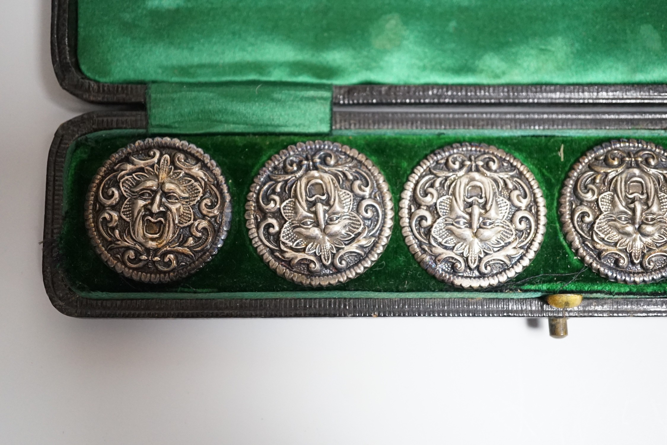 A cased set of six Edwardian silver buttons, each embossed with a mask, Henry Matthews, Birmingham, 1902, 27mm.